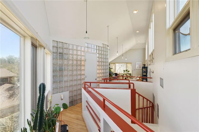 hallway featuring recessed lighting, vaulted ceiling, plenty of natural light, and wood finished floors