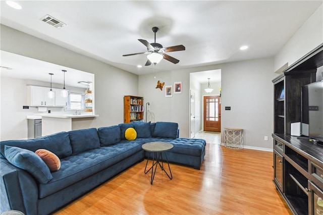 living room featuring visible vents, baseboards, a ceiling fan, light wood-style flooring, and recessed lighting