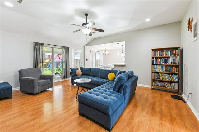 living room with light wood finished floors, baseboards, and ceiling fan with notable chandelier