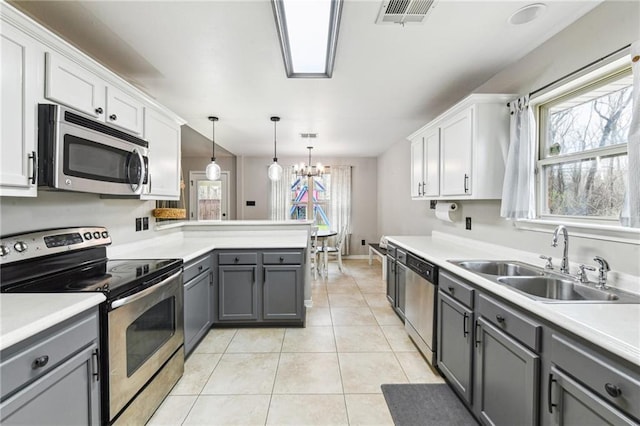 kitchen featuring visible vents, appliances with stainless steel finishes, gray cabinets, a sink, and light tile patterned flooring