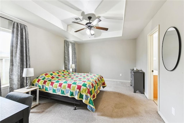 carpeted bedroom featuring a tray ceiling, a ceiling fan, and baseboards