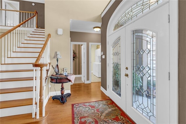 foyer entrance with baseboards, stairway, wood finished floors, crown molding, and french doors