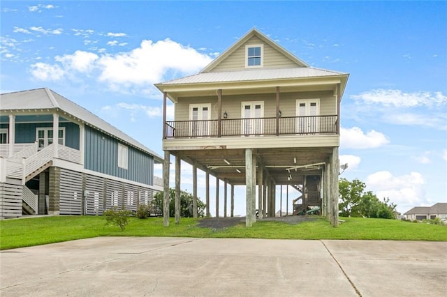 coastal inspired home featuring stairs, concrete driveway, and a front lawn