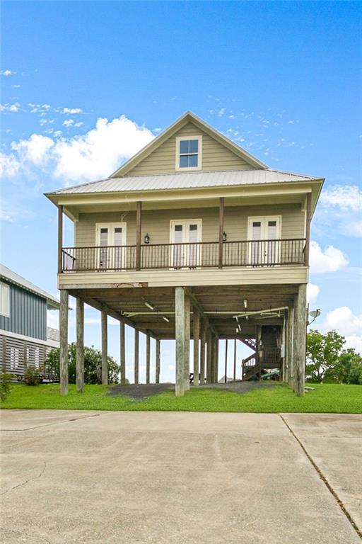 view of front facade featuring covered porch, concrete driveway, french doors, a carport, and a front lawn