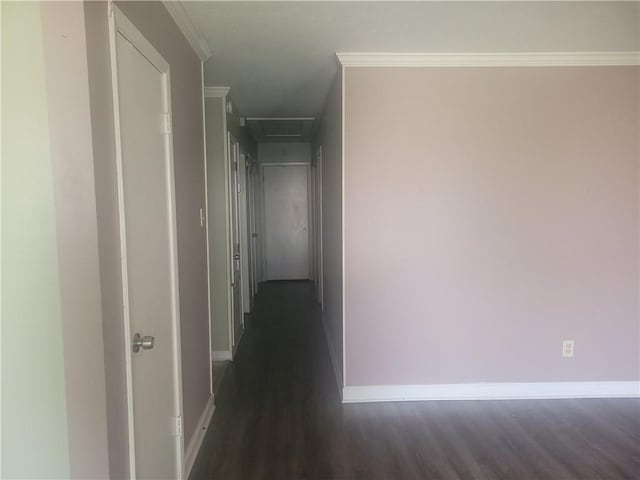 hallway featuring baseboards, dark wood-style flooring, attic access, and crown molding