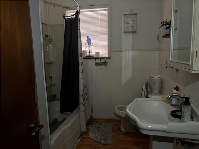 bathroom with shower / tub combo with curtain, toilet, wainscoting, a sink, and wood finished floors