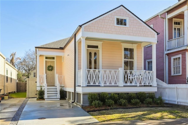 view of front of property with a porch, fence, and a shingled roof