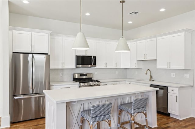 kitchen featuring stainless steel appliances, a center island, white cabinets, and a sink