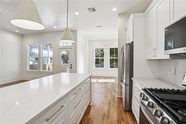 kitchen featuring dark wood-style floors, stainless steel appliances, a wealth of natural light, and white cabinets