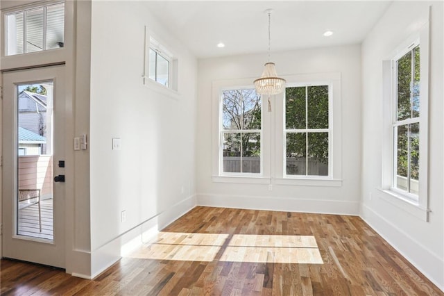 unfurnished dining area featuring a healthy amount of sunlight, baseboards, and wood finished floors