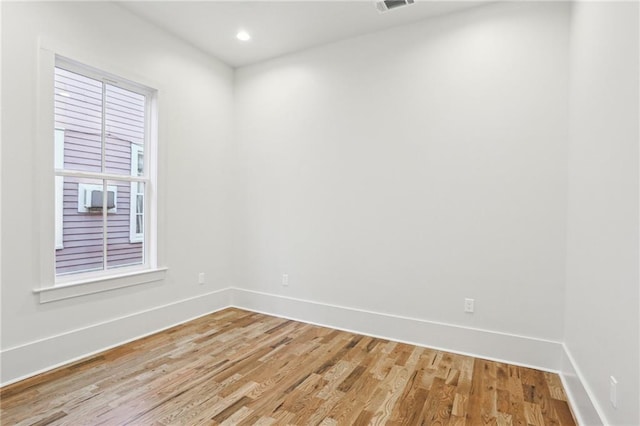 empty room with light wood-style floors, recessed lighting, visible vents, and baseboards