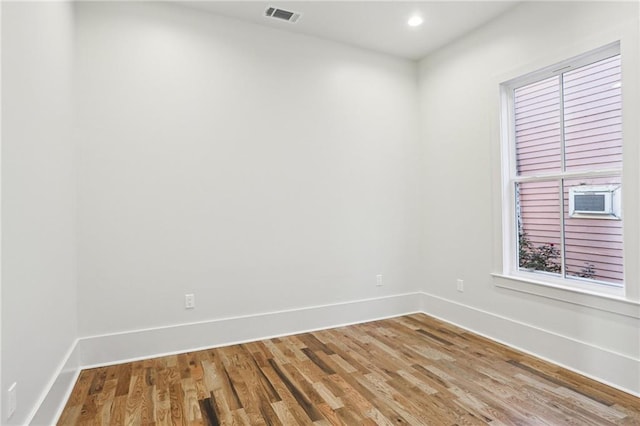 spare room featuring a wealth of natural light, visible vents, baseboards, and wood finished floors