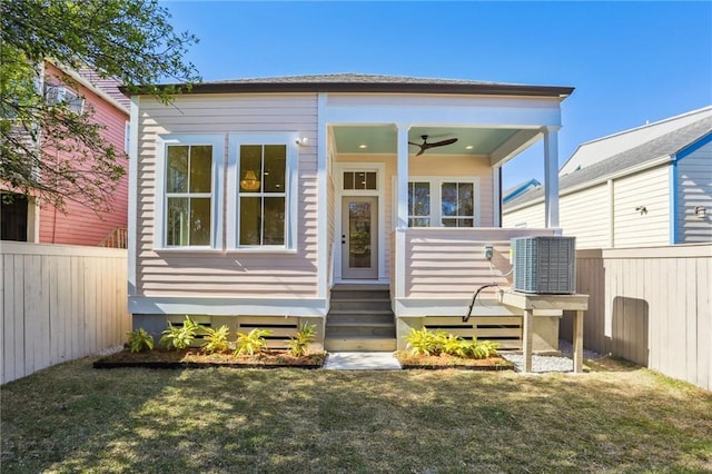 view of front of property with a ceiling fan, cooling unit, fence, and a front yard