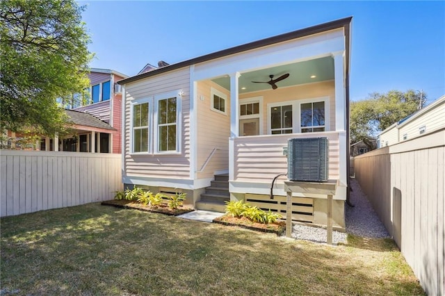 back of property featuring fence private yard, a yard, and ceiling fan