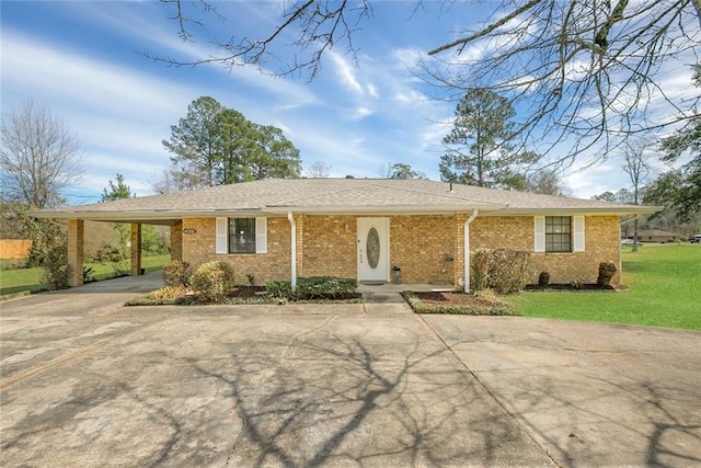 single story home featuring a carport, concrete driveway, brick siding, and a front lawn