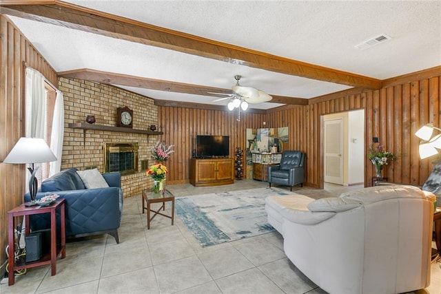 living area with a textured ceiling, a brick fireplace, visible vents, and wooden walls