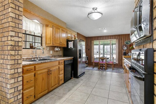 kitchen with dishwasher, stainless steel fridge with ice dispenser, a textured ceiling, wood walls, and a sink