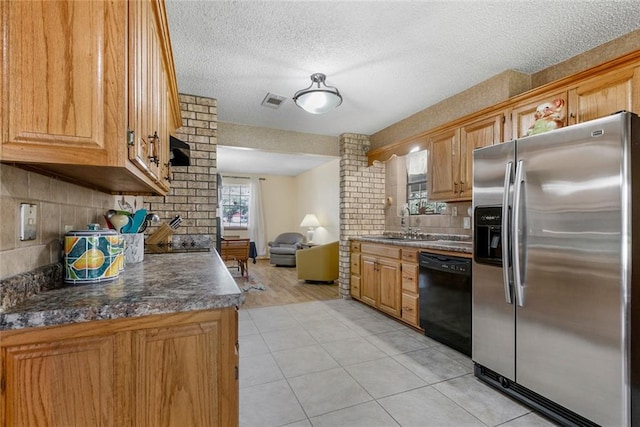 kitchen featuring stainless steel refrigerator with ice dispenser, dark countertops, light tile patterned flooring, a sink, and dishwasher