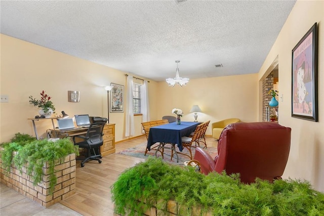 home office with a chandelier, visible vents, a textured ceiling, and light wood-style flooring