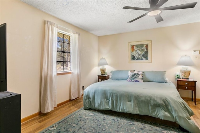 bedroom with a textured ceiling, ceiling fan, wood finished floors, and baseboards