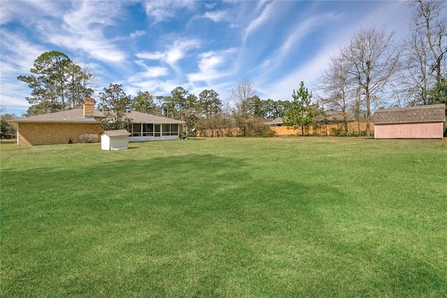 view of yard featuring a sunroom, a shed, and an outdoor structure