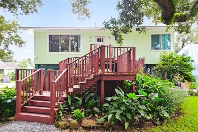 view of front facade with stairs, a deck, and stucco siding