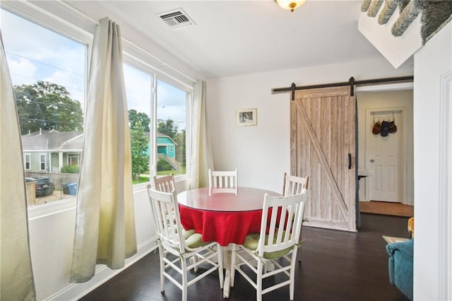 dining space with baseboards, a barn door, visible vents, and wood finished floors