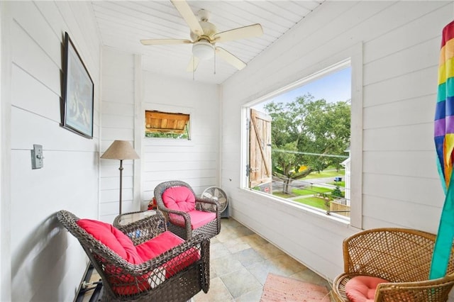 living area featuring wood walls and ceiling fan