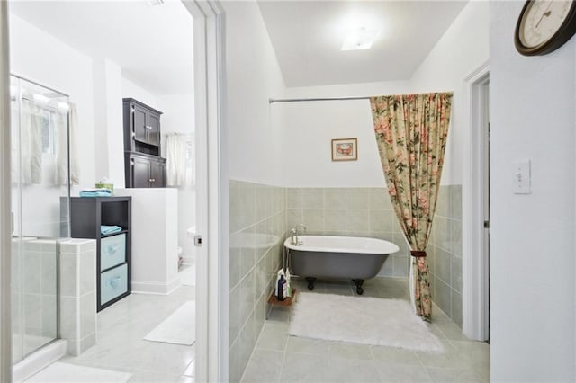 bathroom with tile walls, wainscoting, a shower stall, tile patterned flooring, and a freestanding tub