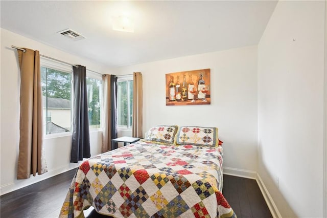 bedroom with dark wood-style flooring, visible vents, and baseboards