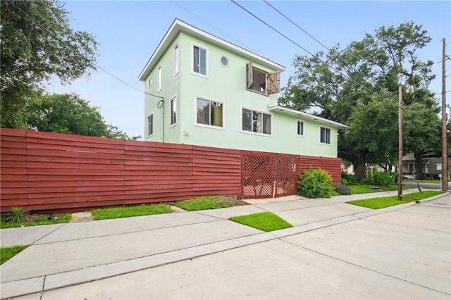 view of side of property with fence and stucco siding