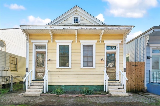 shotgun-style home featuring entry steps and fence