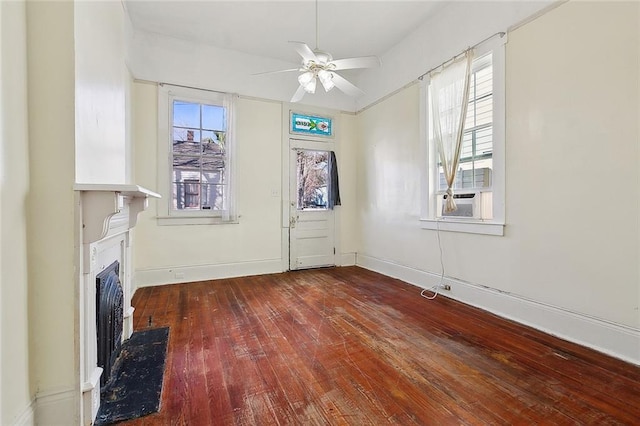 unfurnished living room featuring a fireplace with flush hearth, hardwood / wood-style flooring, cooling unit, baseboards, and ceiling fan