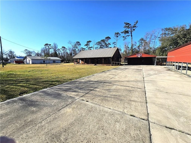 exterior space featuring driveway, a lawn, a pole building, an outdoor structure, and a carport