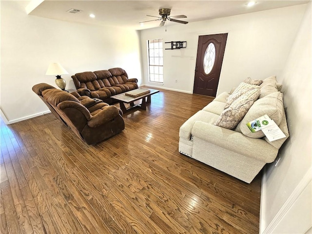 living area featuring a ceiling fan, dark wood finished floors, and baseboards