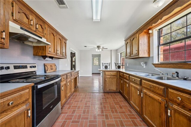 16685 Meissner Rd, Springfield, LA 70462 - kitchen with under cabinet range hood, a sink, stainless steel range with electric cooktop, visible vents, and brown cabinetry