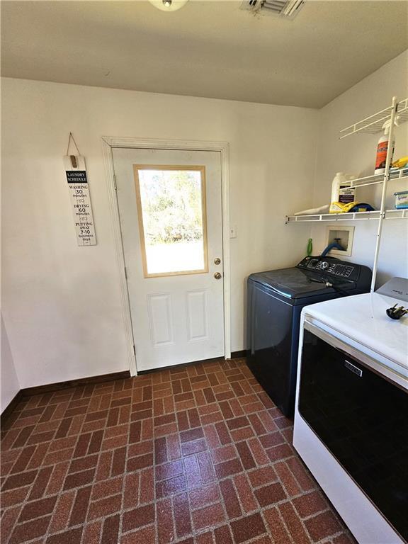 washroom with brick floor, laundry area, baseboards, and separate washer and dryer