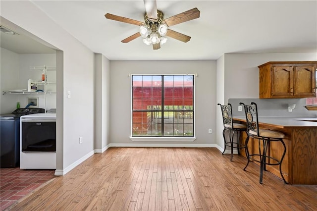 16685 Meissner Rd, Springfield, LA 70462 - kitchen featuring washing machine and dryer, wood finished floors, brown cabinets, baseboards, and ceiling fan