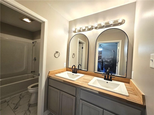 bathroom with marble finish floor, a sink, toilet, and double vanity