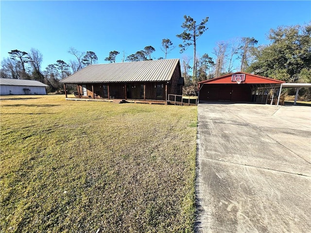 view of front of house with driveway, metal roof, an outbuilding, a front lawn, and a carport