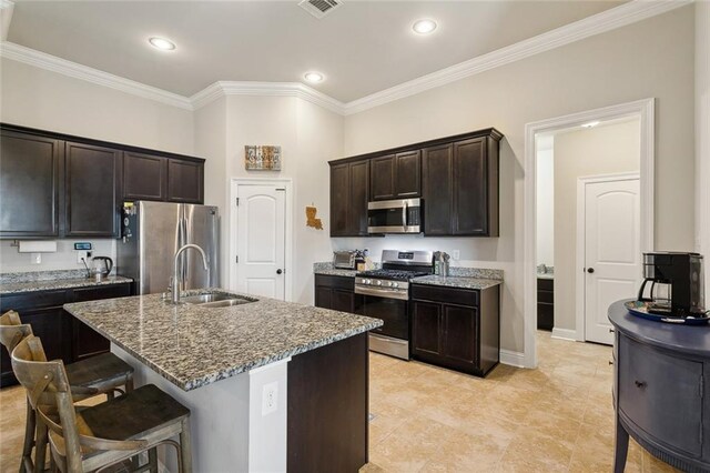 kitchen with appliances with stainless steel finishes, a kitchen breakfast bar, light stone countertops, crown molding, and a sink