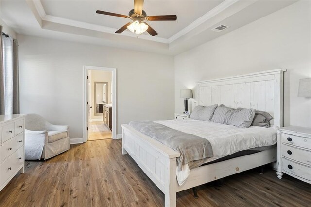 bedroom with ornamental molding, a raised ceiling, visible vents, and wood finished floors