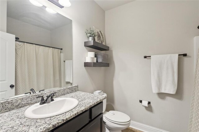 full bathroom with vanity, toilet, and baseboards