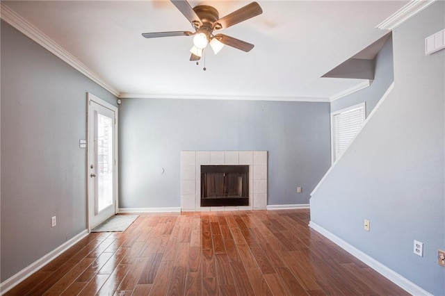 unfurnished living room featuring ornamental molding, baseboards, a tiled fireplace, and wood finished floors