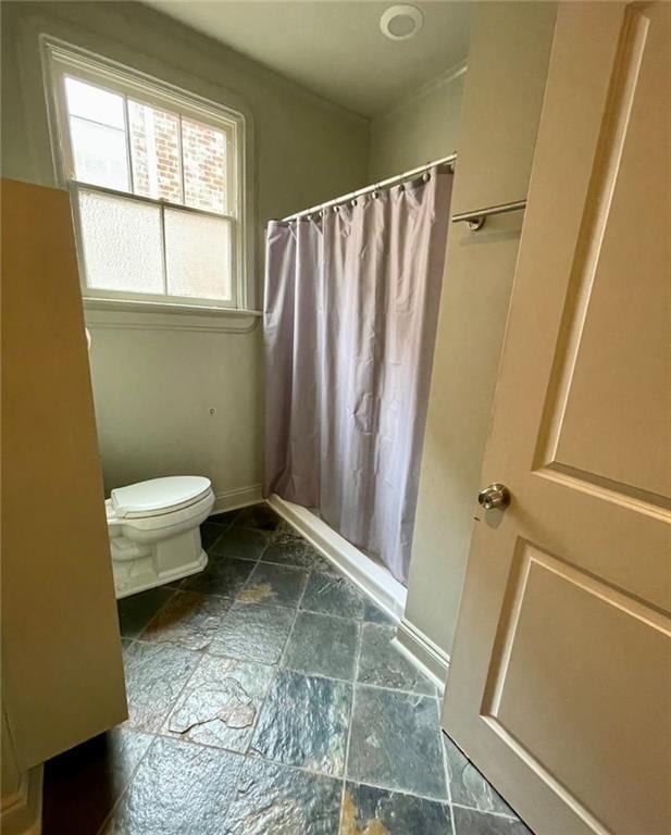 312 W Robert E Lee Blvd, New Orleans, LA 70124 - bathroom with stone finish flooring, toilet, baseboards, and a shower with curtain