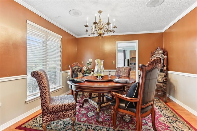 dining area featuring wood finished floors, baseboards, ornamental molding, a textured ceiling, and a notable chandelier