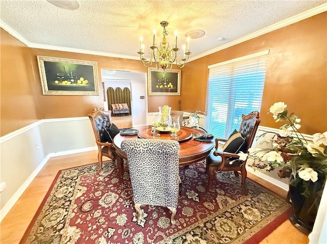 dining space featuring baseboards, a chandelier, ornamental molding, light wood-style floors, and a textured ceiling