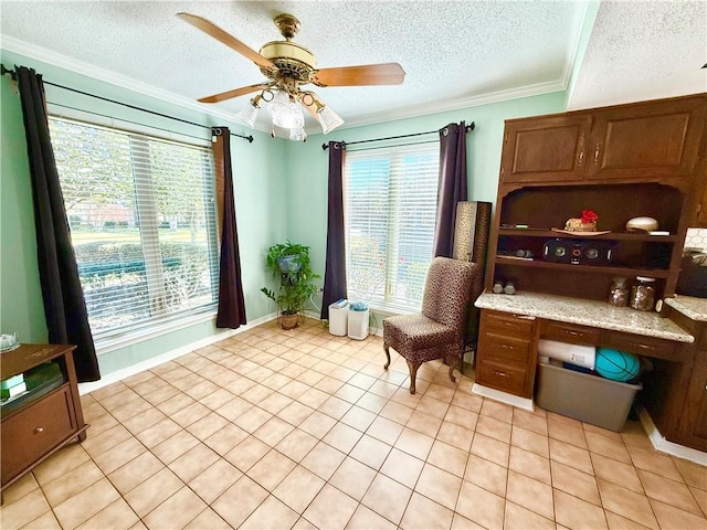 interior space featuring crown molding, a ceiling fan, built in desk, and a wealth of natural light