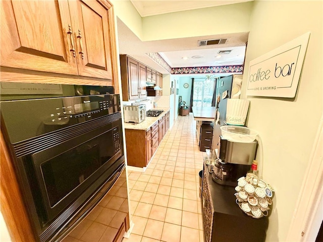 5 Five Oaks Dr, New Orleans, LA 70131 - kitchen featuring oven, gas stovetop, light tile patterned floors, ornamental molding, and brown cabinets