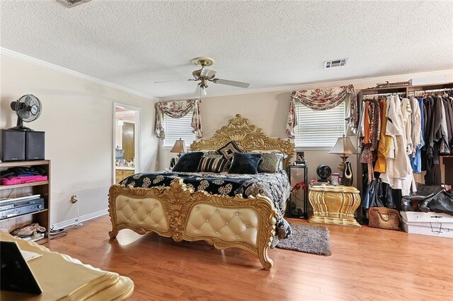 bedroom featuring multiple windows, wood finished floors, visible vents, and ornamental molding